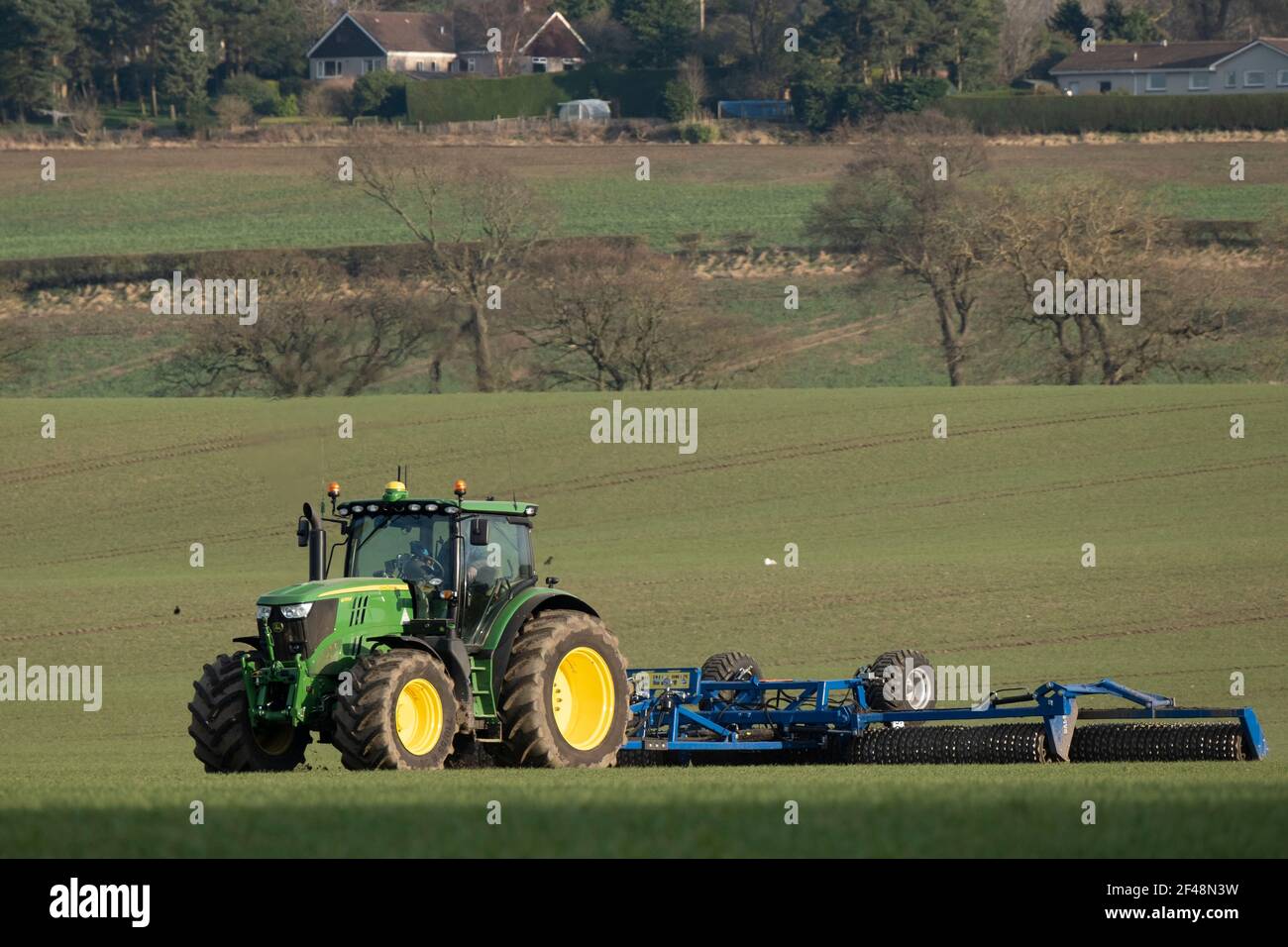 Un trattore John Deere traina una macchina per la preparazione del raccolto in un campo coltivato, West Lothian, Scozia. Foto Stock