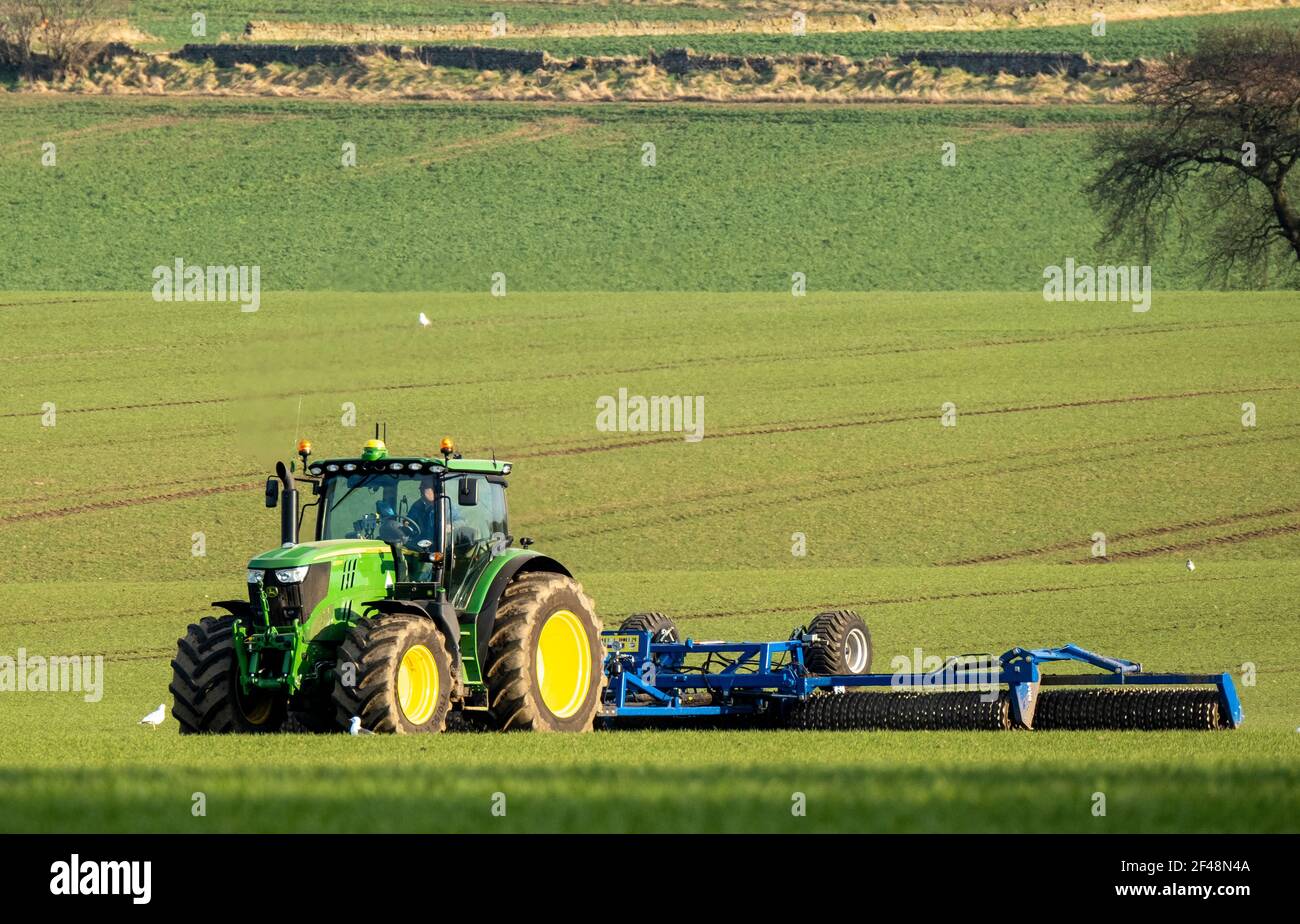 Un trattore John Deere traina una macchina per la preparazione del raccolto in un campo coltivato, West Lothian, Scozia. Foto Stock