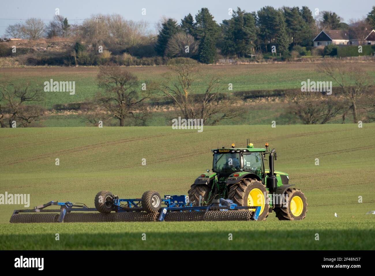Un trattore John Deere traina una macchina per la preparazione del raccolto in un campo coltivato, West Lothian, Scozia. Foto Stock
