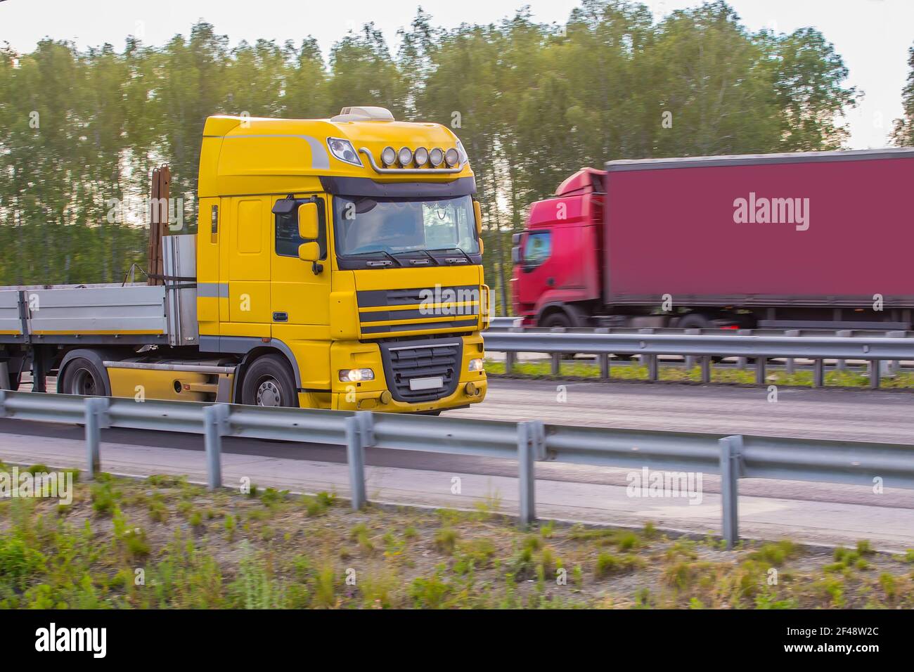 I camion pesanti si muovono lungo la strada rurale in direzioni diverse. Foto Stock