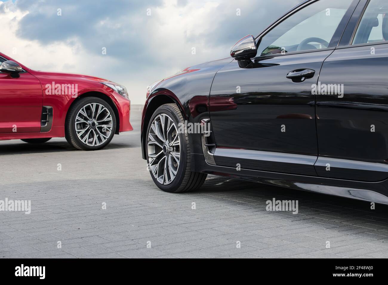 auto di lusso rosse e nere contro il cielo blu nuvoloso Foto Stock