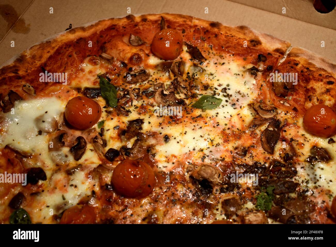 Pizza con funghi e pomodori ciliegini Foto Stock