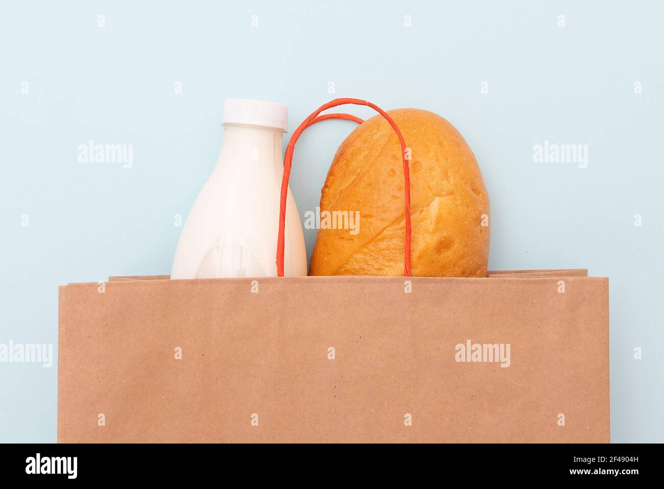 Sacchetto di carta con bottiglia di latte e pane, pane bianco su sfondo blu Foto Stock