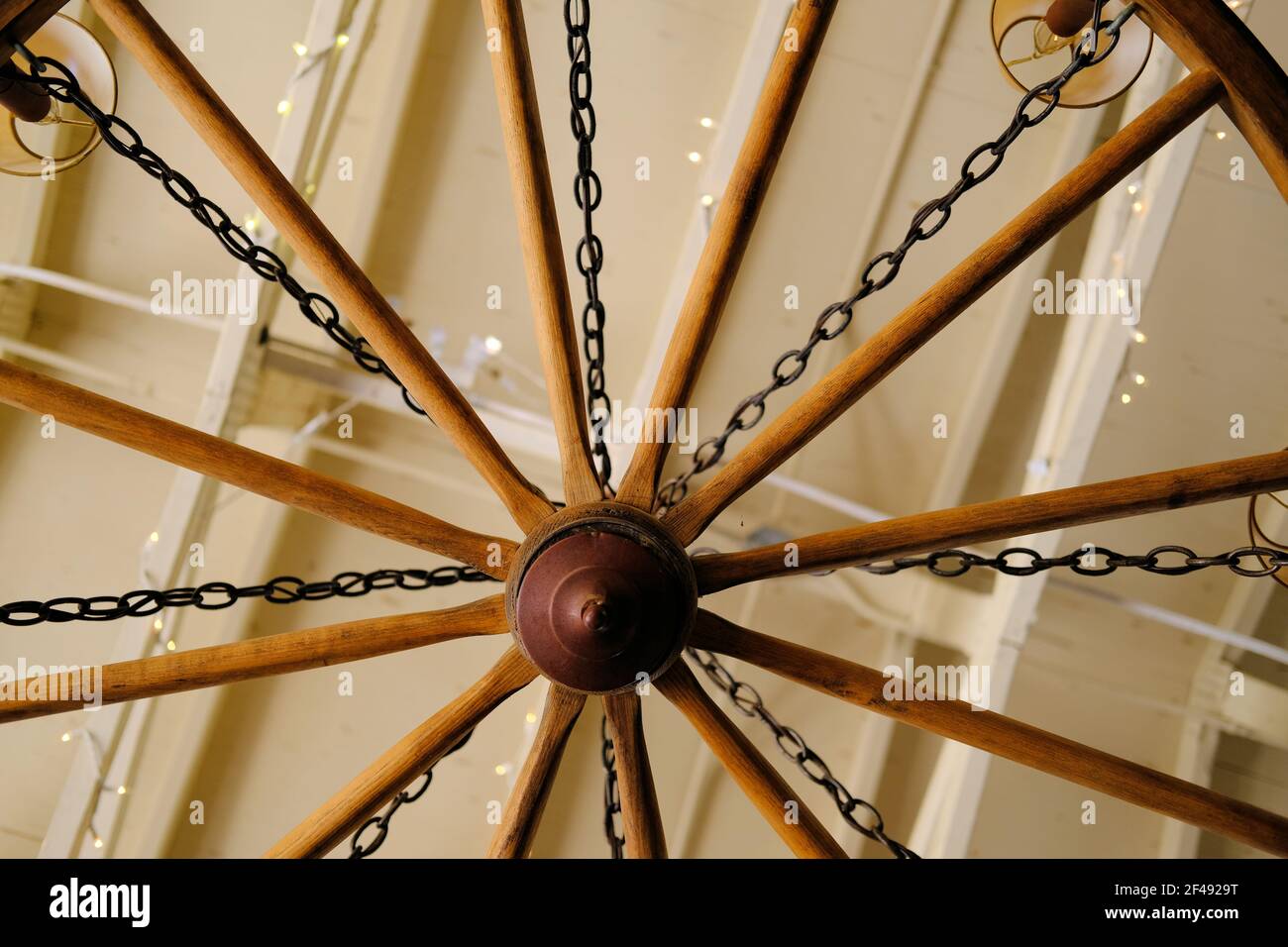Vista dal basso di una ruota di un carro trasformata in un lampadario di luce; arredamento e design interni rustici. Foto Stock