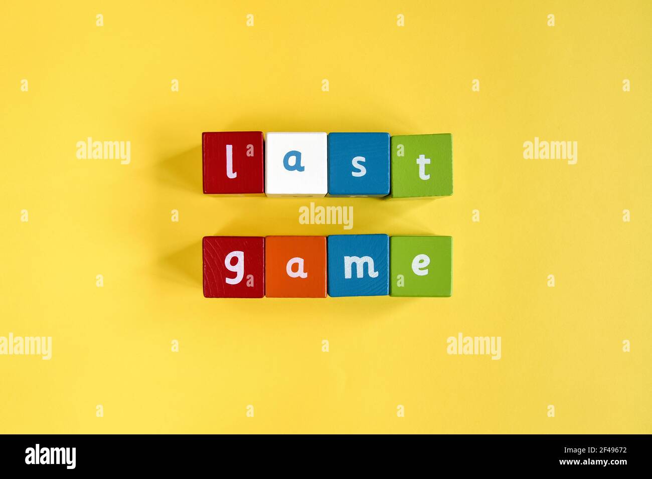Parole ultimo gioco fatto da blocchi di legno colorati. Sono disposte in due file. Cubi dipinti con lettere su sfondo giallo. Vista dall'alto. Foto Stock