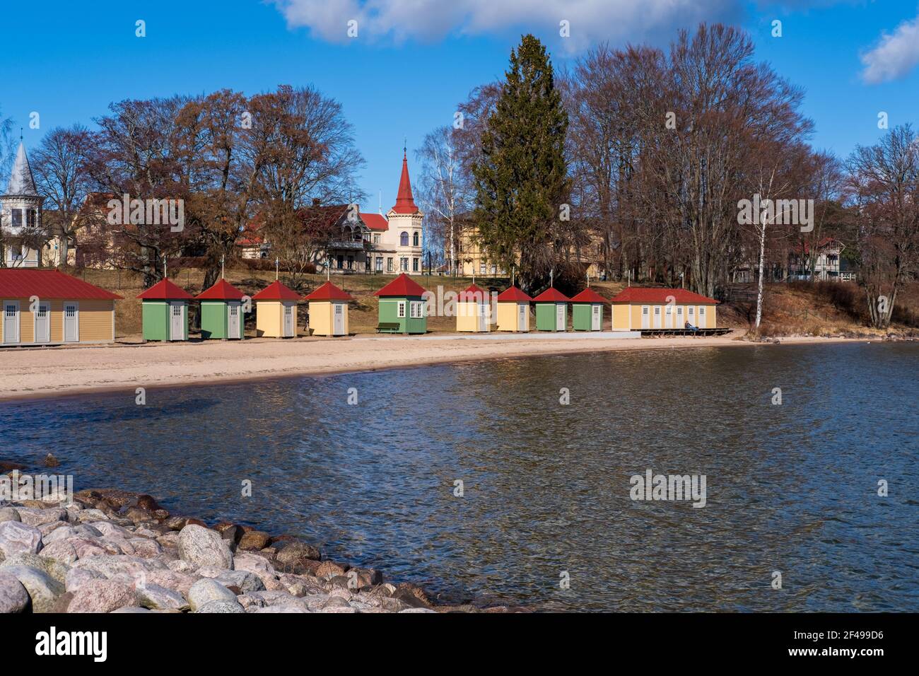 Colorate cabine da bagno allineate accanto alla spiaggia di sabbia numerata in numeri roaman con la città di Hjo in background, Svezia Foto Stock