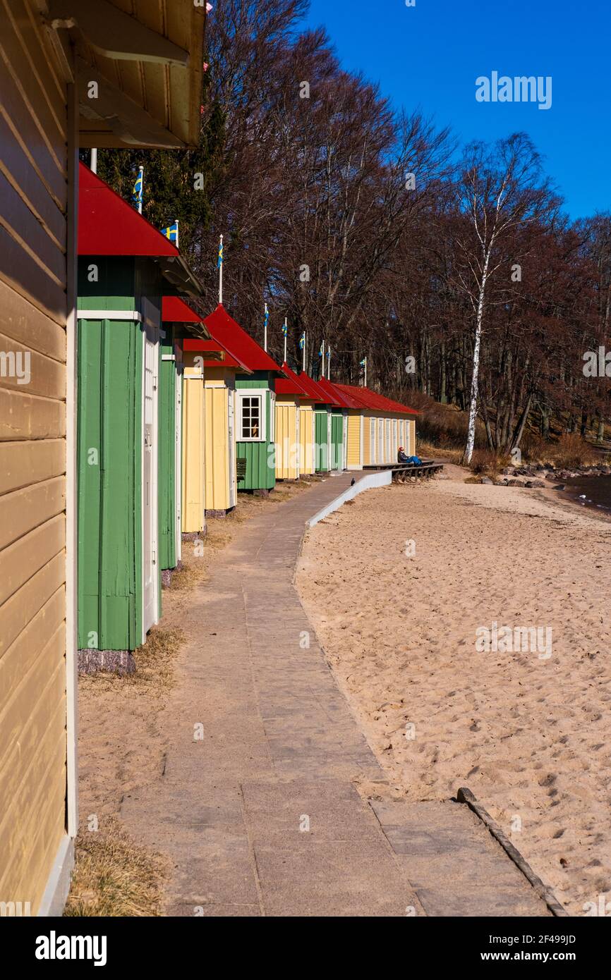 Colorate cabine da bagno allineate accanto alla spiaggia di sabbia numerate in numeri roaman a Hjo, Svezia Foto Stock