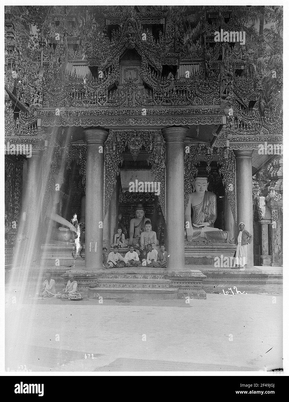 Rangonn, Birmania: Scena nella Pagoda Shwedagon. I giovani sono incorniciati da due colonne, oltre a colonne, grande statua di Buddha con locale; 5 giovani uomini seduti in sede taglierina contro Buddhstatuen sotto il tetto a colonne della pagoda Schwedagon Foto Stock