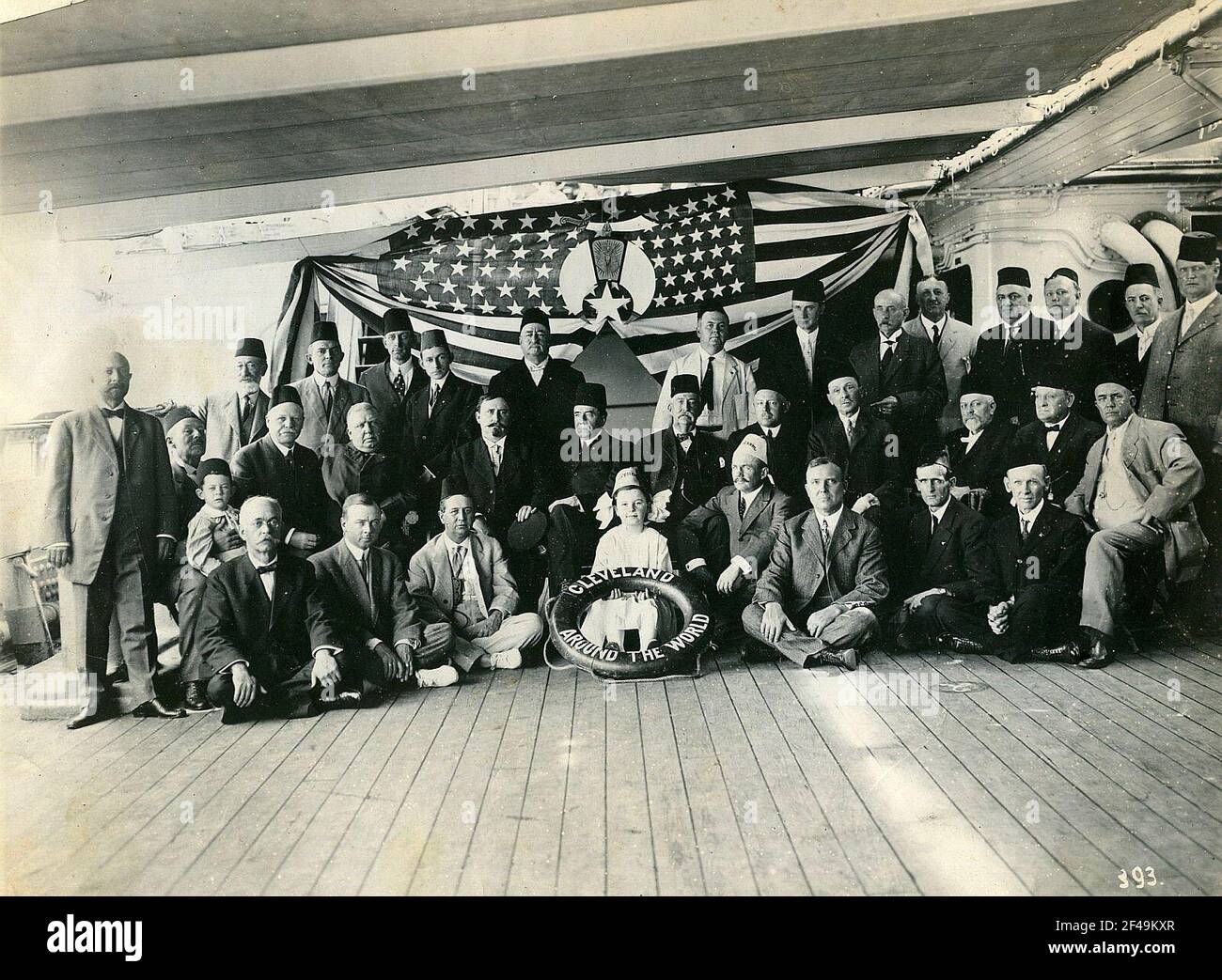 Formazione di gruppo con il Fest che sostiene il Signore sul ponte di decleveland contro la bandiera americana con emblema egiziano. Nel mezzo piccola ragazza con stile di vita (Cleveland intorno al mondo) e Fes con l'iscrizione Siria, accanto ad esso un Signore con Fes Salaam Foto Stock