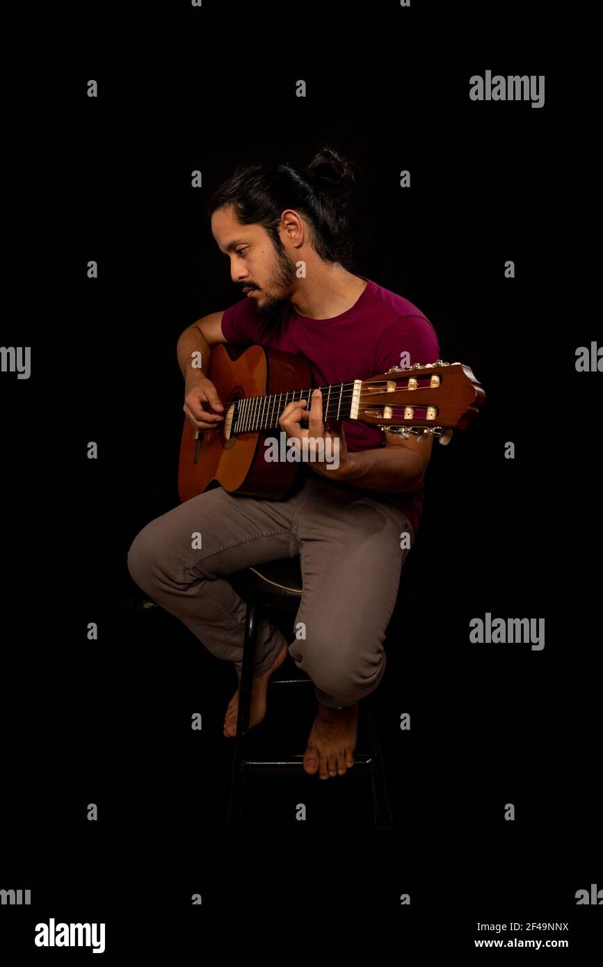 Uomo che suona una chitarra acustica con sfondo nero Foto Stock