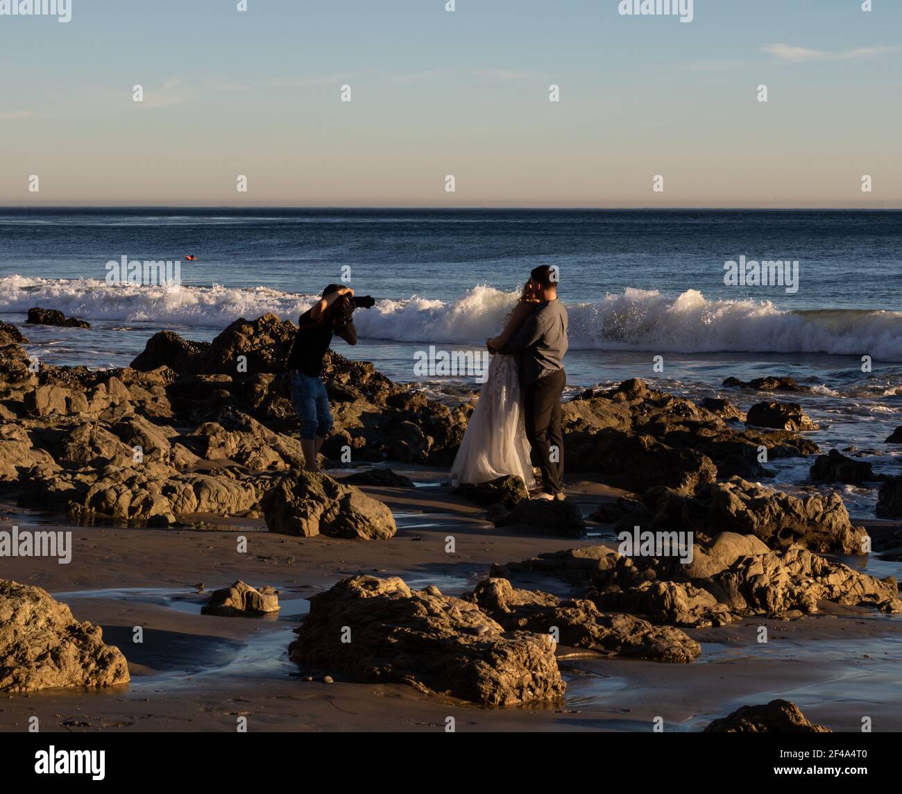 Malibu, CA USA - 1 marzo 2021: Vista ravvicinata di un fotografo che scatta foto di una coppia appena sposata sulla spiaggia di El Matador Foto Stock