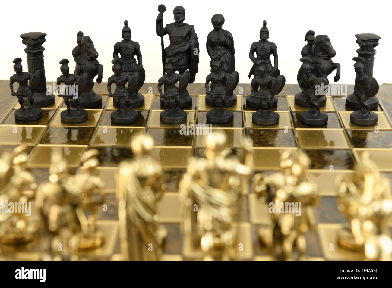 Nero contro i pezzi di scacchi del soldato dell'esercito dell'oro su una scacchiera su sfondo bianco Foto Stock