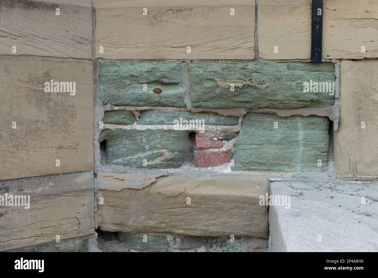 Sbriciolare e eroso marrone e verde pietra calcarea che rivela mattoni dietro e Malta più resistente, effetti di pioggia acida, aspetto orizzontale Foto Stock