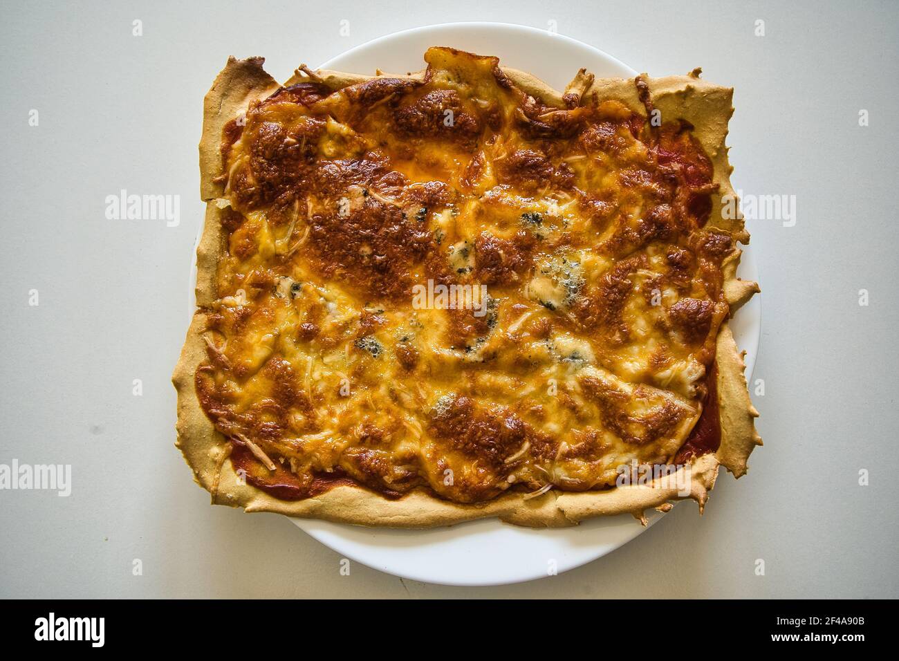 Deliziosa pizza italiana calda fatta in casa pronta a mangiare. Con pomodoro, prosciutto, mozzarella e quattro formaggi. Gusto Foto Stock