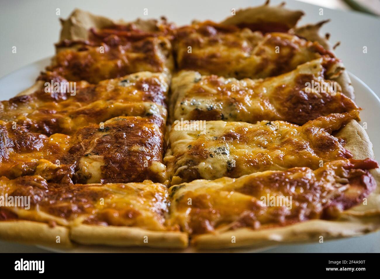 Deliziosa pizza italiana calda fatta in casa pronta a mangiare. Con pomodoro, prosciutto, mozzarella e quattro formaggi. Gusto Foto Stock