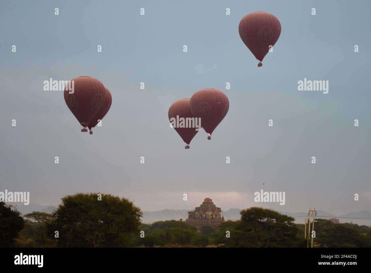 BAGAN, NYAUNG-U, MYANMAR - 2 GENNAIO 2020: Alcuni mongolfiera si erge sopra uno storico tempio pagoda in lontananza Foto Stock