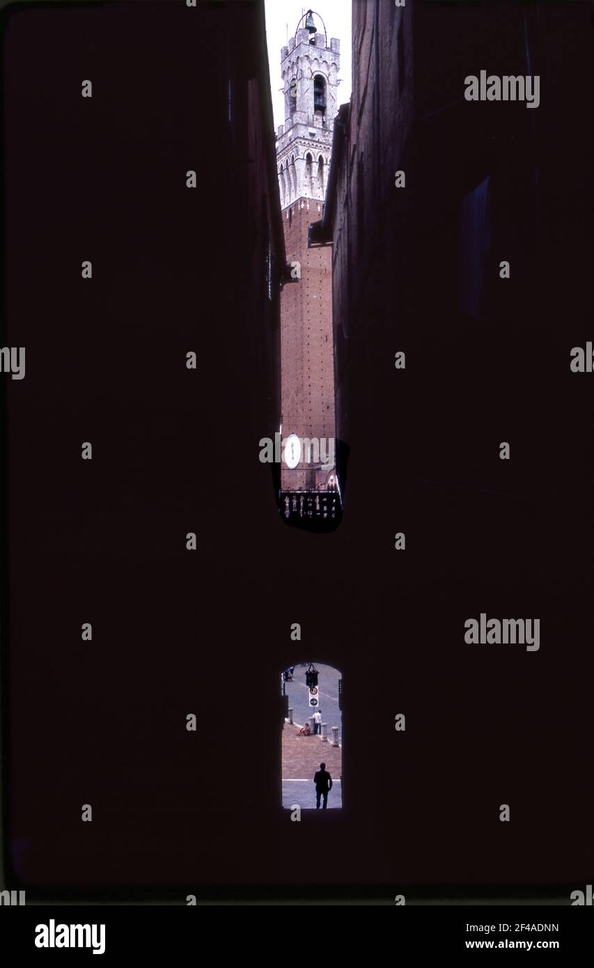 Campanile a Siena, Italia visto attraverso edifici su una stradina che conduce al campo. Foto Stock