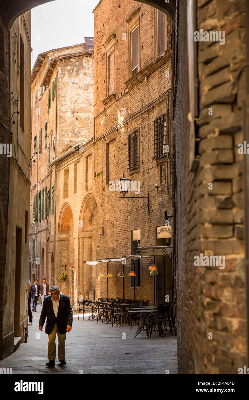 Siena, Italia. Uomini italiani che camminano in una strada stretta. (Solo per uso editoriale) Foto Stock