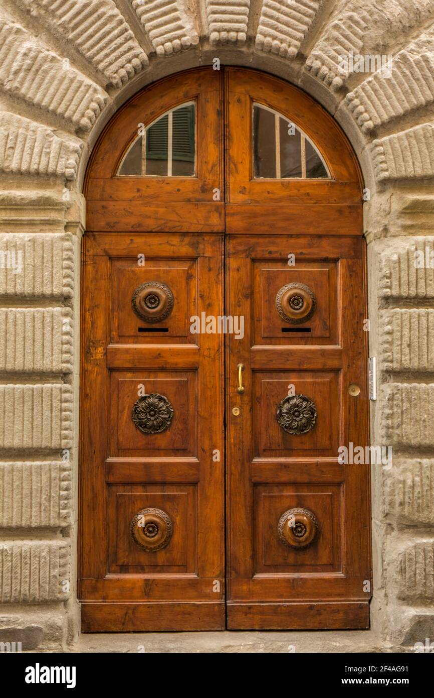 Cortona, Toscana, Italia. Porta decorativa in legno con lunetta segmentata in una casa in pietra. (Solo per uso editoriale) Foto Stock