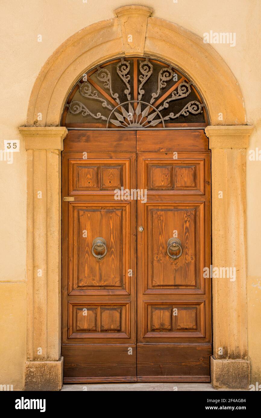 Pienza, Toscana, Italia. Porta decorativa in legno con lunetta segmentata in una casa in pietra. (Solo per uso editoriale) Foto Stock