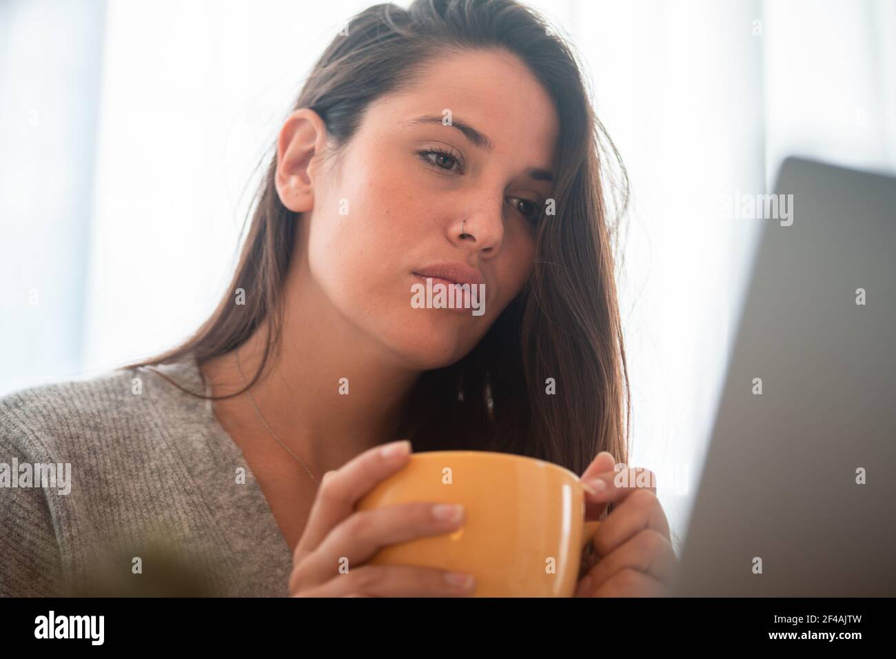 giovane donna telelavoro a casa con il computer che beve caffè Foto Stock