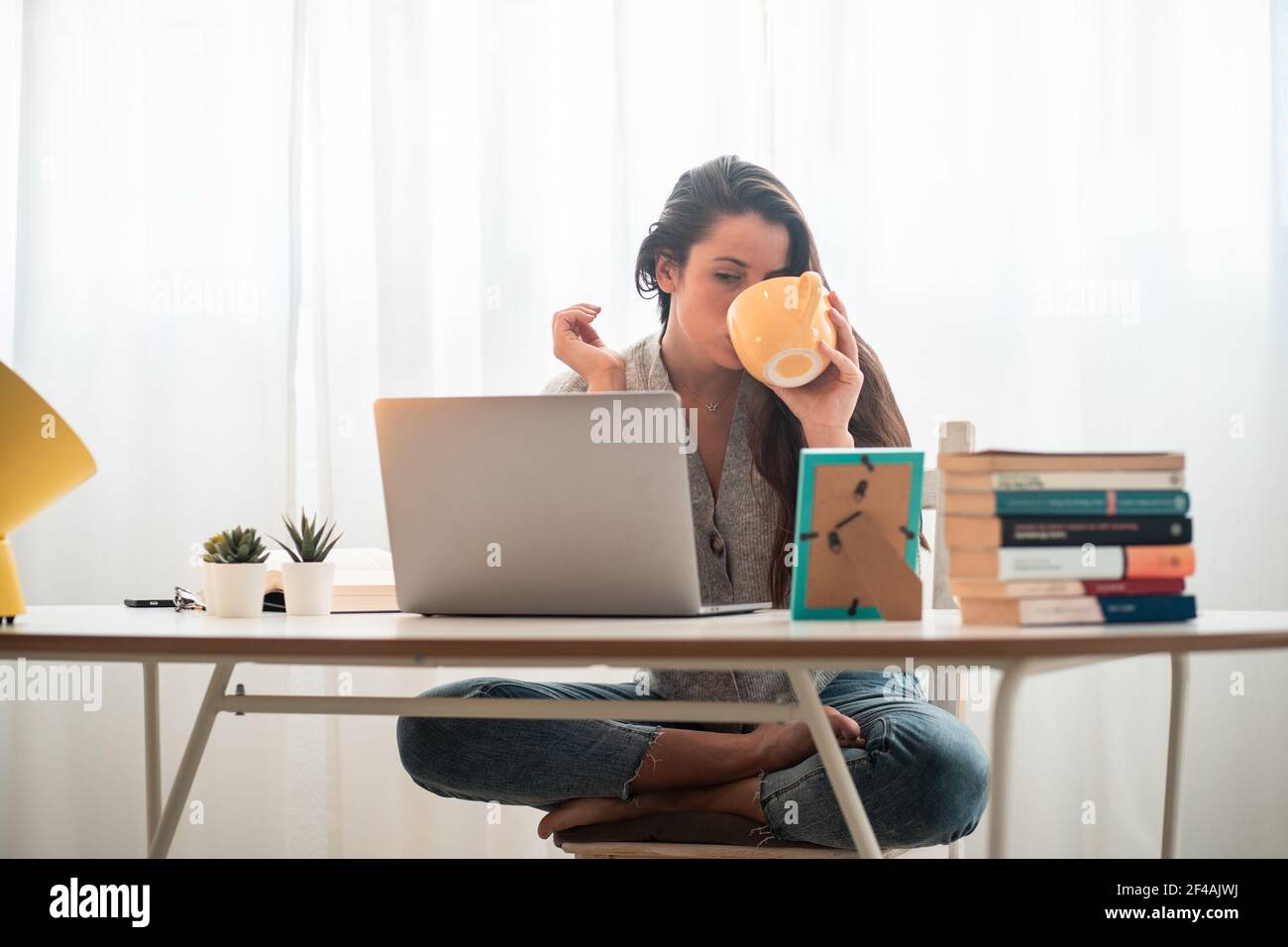 giovane donna telelavoro a casa con il computer che beve caffè Foto Stock