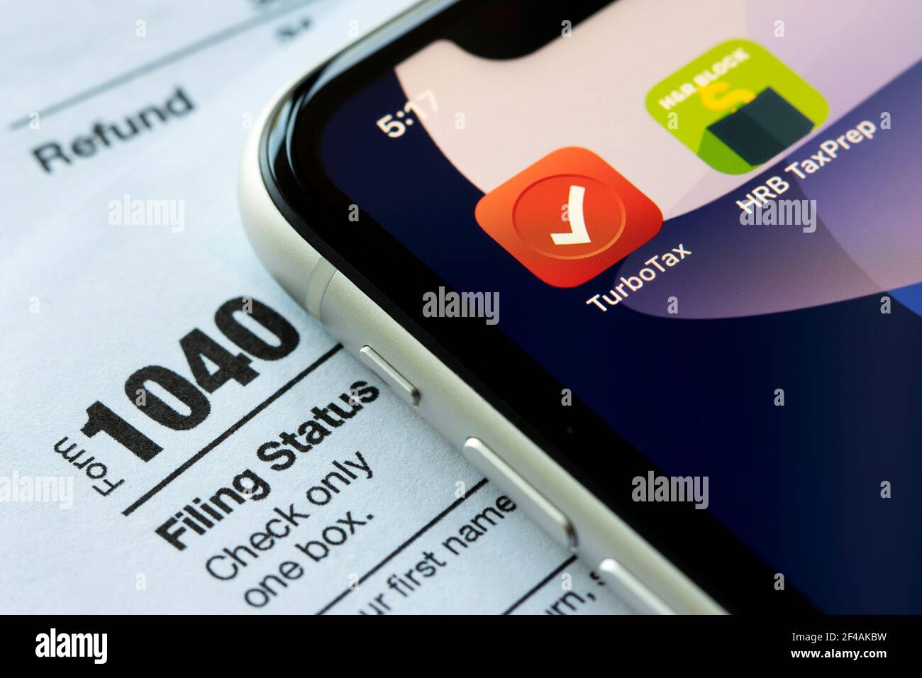 Le icone dell'app mobile TurboTax e HRB Tax Prep vengono visualizzate su un iPhone, con il modulo 1040, il rendimento delle imposte sul reddito individuale degli Stati Uniti, sullo sfondo. Foto Stock