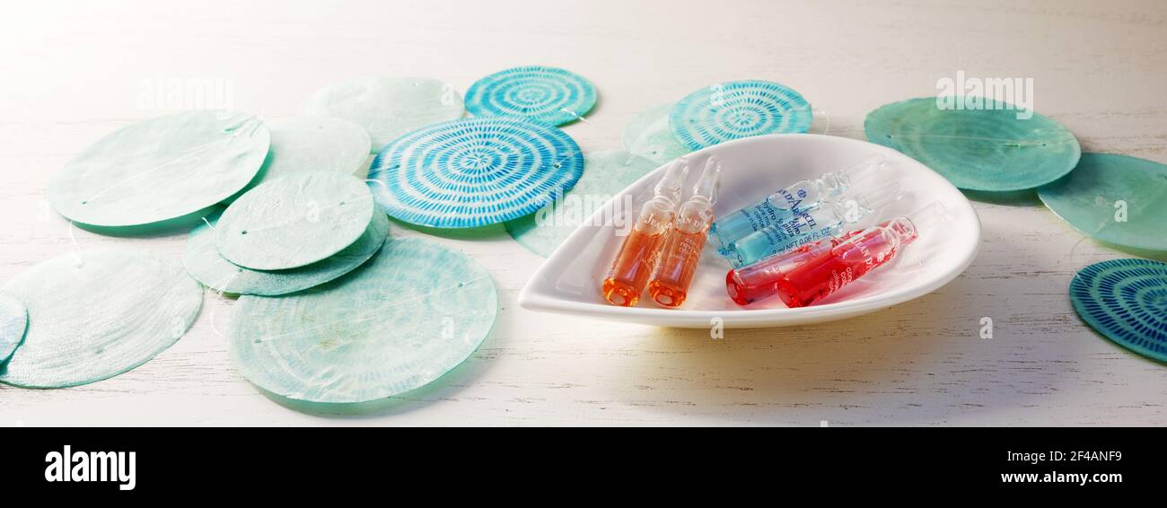 Ampolle per un lussuoso trattamento cosmetico di bellezza da Jean d Arcel in una ciotola, dischi a guscio blu e sfondo luminoso, formato panoramico, messa a fuoco selezionata Foto Stock