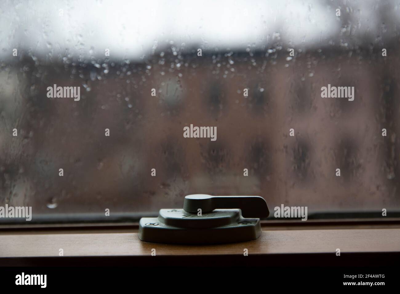 Primo piano del dispositivo di chiusura del finestrino. Hasp. Finestra La pioggia cade su un bicchiere. Foto Stock
