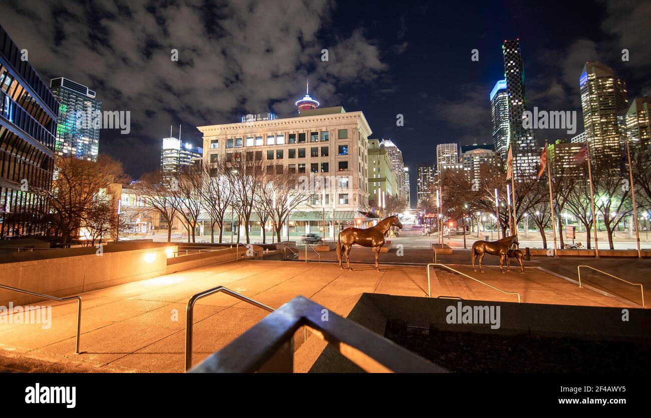 Calgary Alberta Canada, marzo 15 2021: una tranquilla piazza del centro di notte con sculture a cavallo e gli edifici di uffici e i monumenti del centro di notte in un Foto Stock