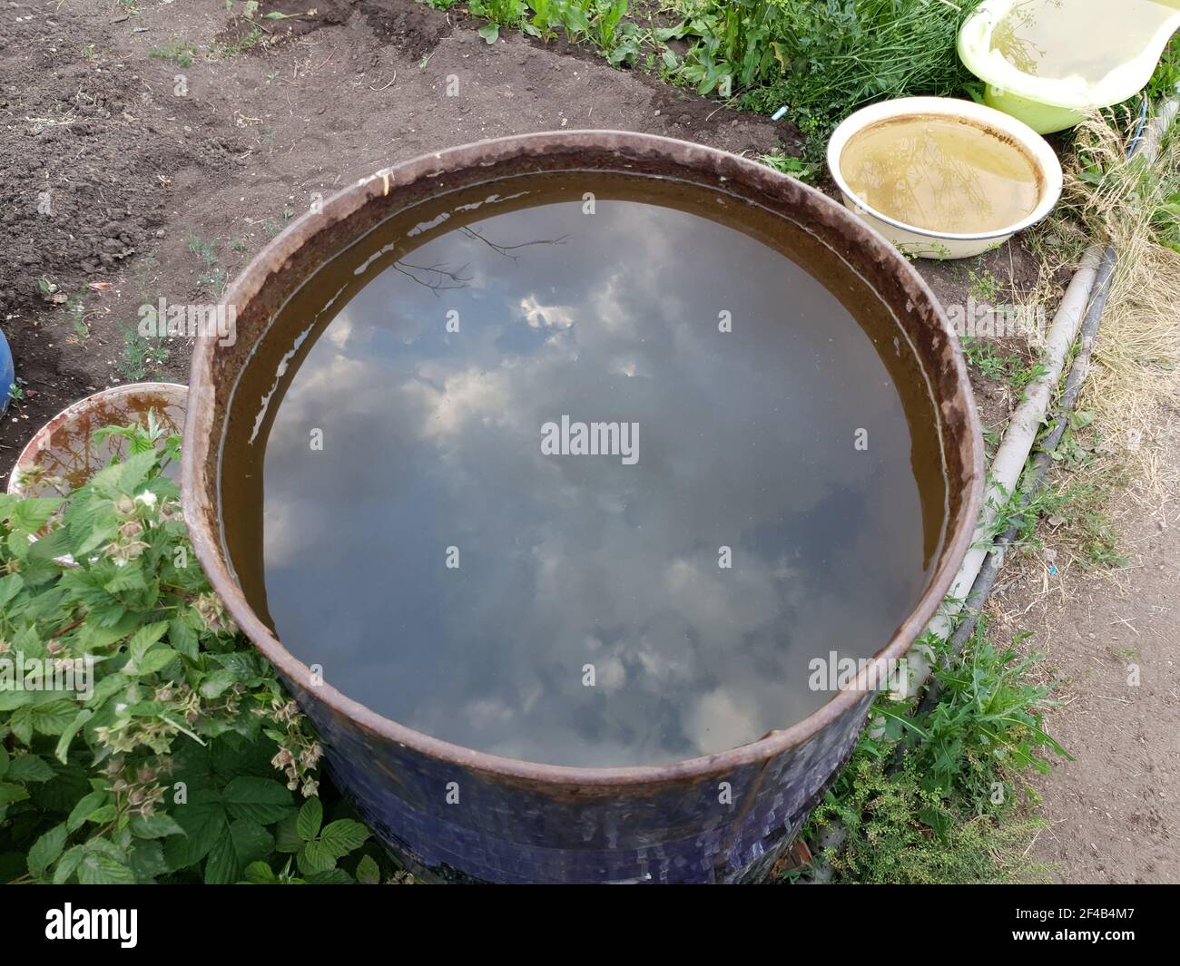 un contenitore con acqua con un riflesso del cielo si alza a terra Foto Stock