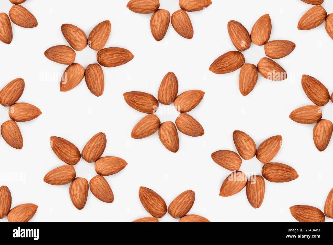 Motivo senza cuciture di fiori di mandorle. 6 mandorle grezze disposte a forma di fiore. Concetto per i benefici per la salute di mangiare noci, dieta a base di piante. Foto Stock