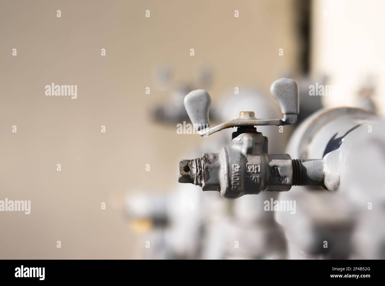 Valvola di chiusura della tubazione del gas naturale, vista laterale. Primo piano sullo sfondo sfocato della tubazione del gas. Concetto di come spegnere il gas naturale in caso di emergenza. Foto Stock