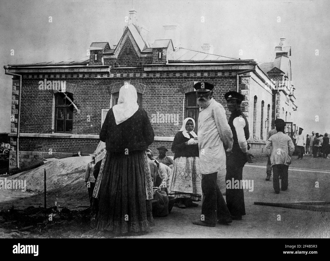 Donne contadine russe e uomini in piedi fuori di un edificio di mattoni, probabilmente durante la guerra mondiale i ca. 1914 Foto Stock