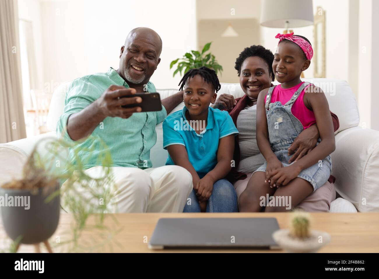 Nonno afro-americano e nonna sul divano sorridendo con i nipoti presa selfie Foto Stock