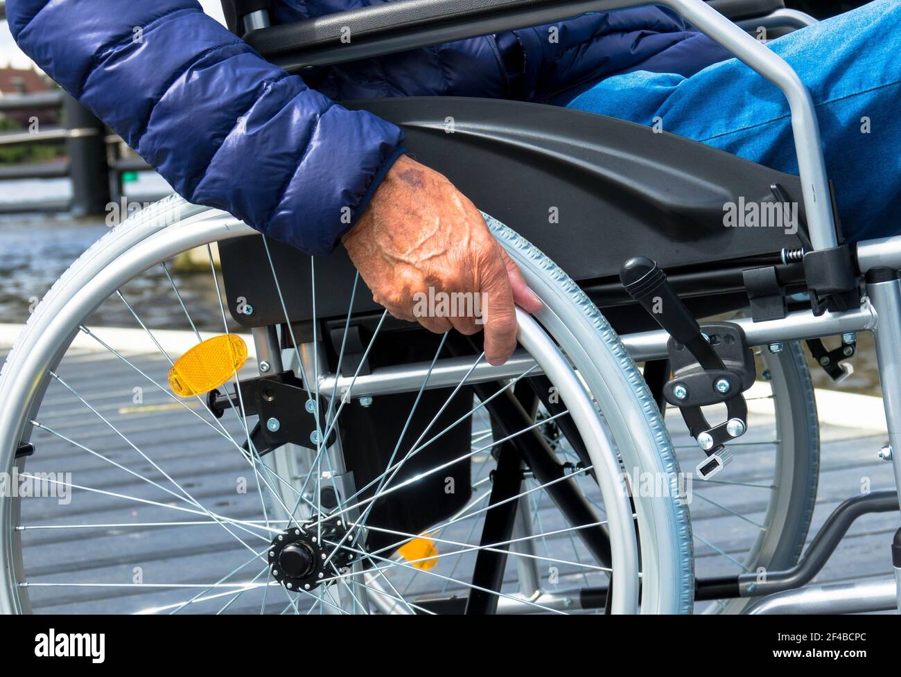 Uomo anziano che usa una sedia a rotelle. Da solo in una casa di riposo. Immagine acquisita durante la pandemia di covidio. Foto Stock