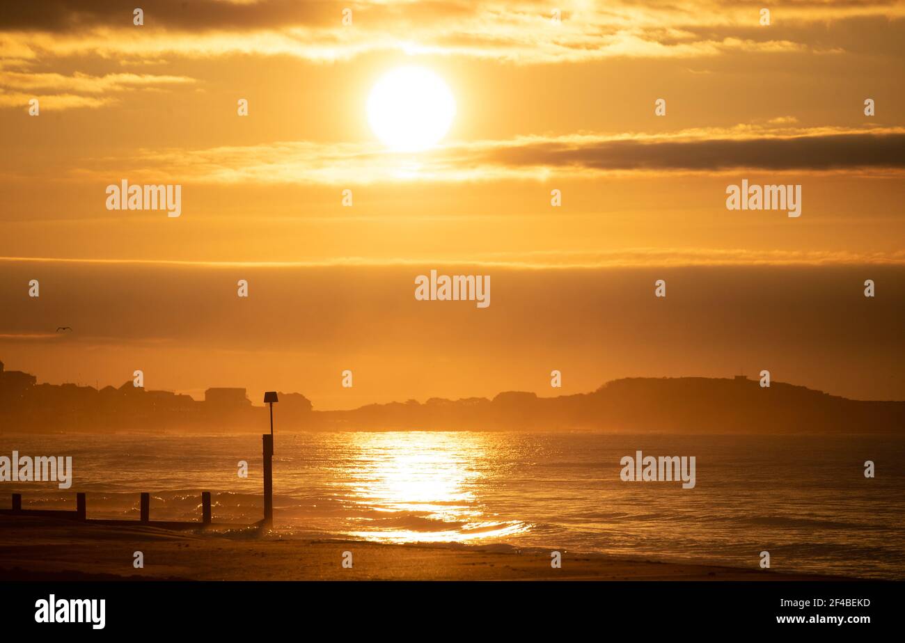 Il sole sorge sulla spiaggia di Boscombe a Dorset il giorno dell'equinozio primaverile. Data immagine: Sabato 20 marzo 2021. Foto Stock