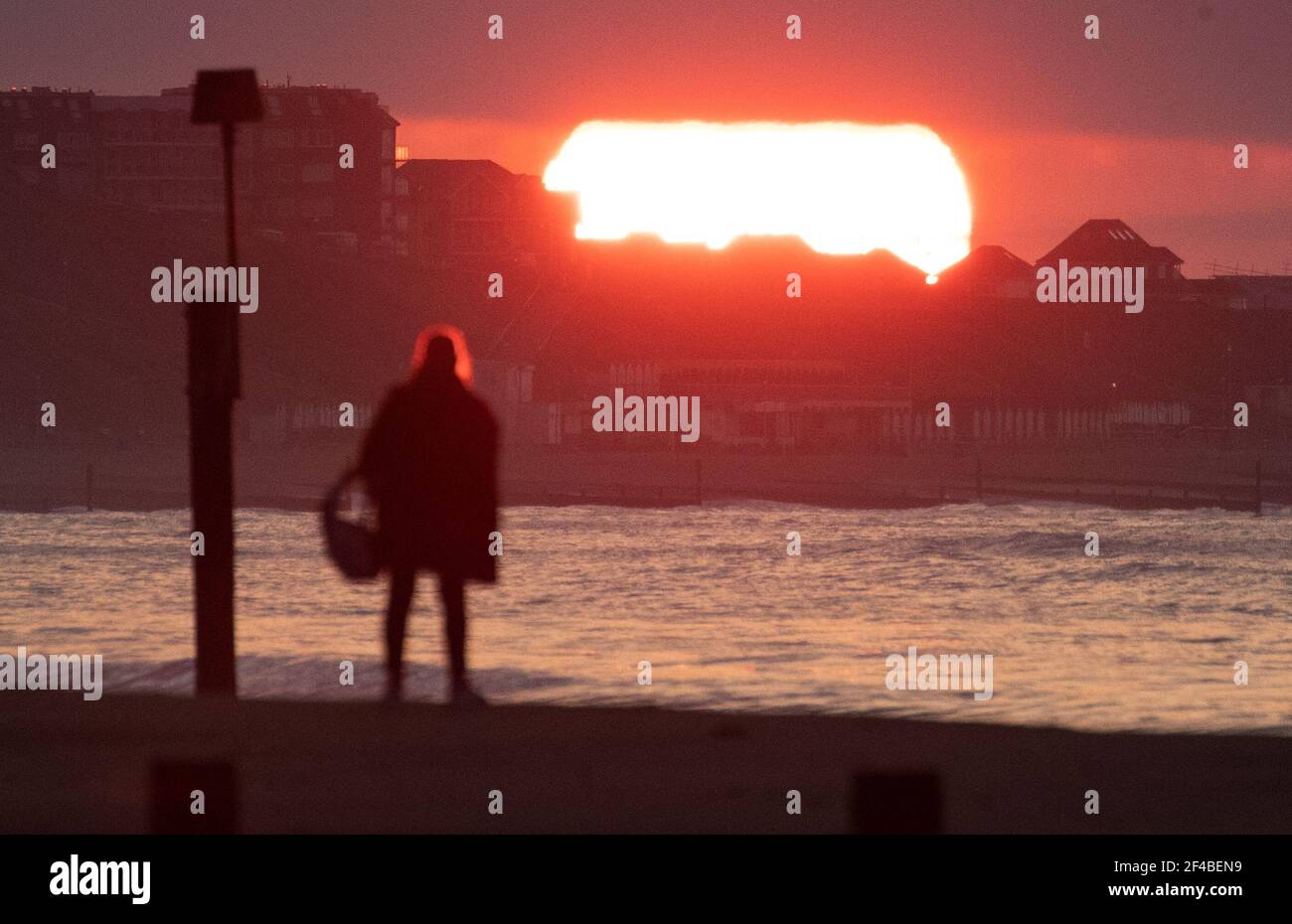 La gente guarda il sole sorgere sulla spiaggia di Boscombe a Dorset il giorno dell'equinozio di primavera. Data immagine: Sabato 20 marzo 2021. Foto Stock