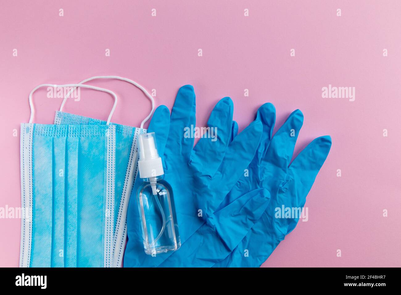 Maschera medica, guanti protettivi e gel antibatterico su sfondo rosa. Pandemia di coronavirus. Foto Stock