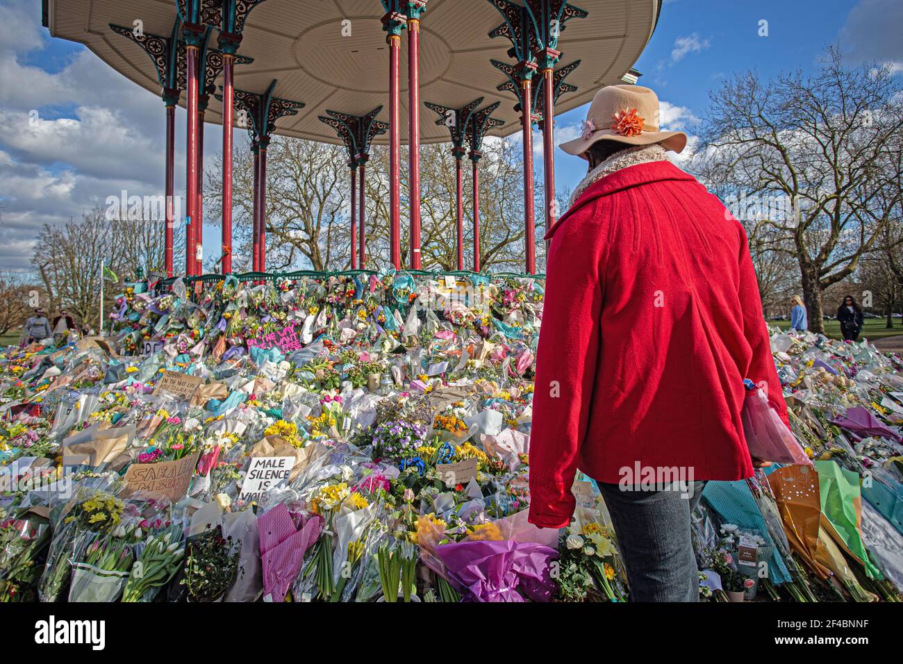 Una donna sta osservando i tributi floreali lasciati al bandstand comune di Clapham dove la gente continua a pagare i loro rispetti a Sarah Everard il 16 marzo 2021 Foto Stock