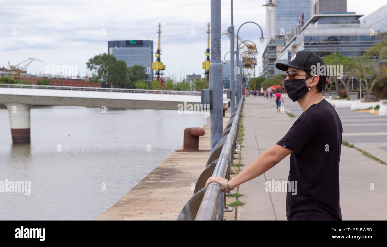 Giovane uomo con maschera facciale e occhiali vicino al fiume. Foto Stock