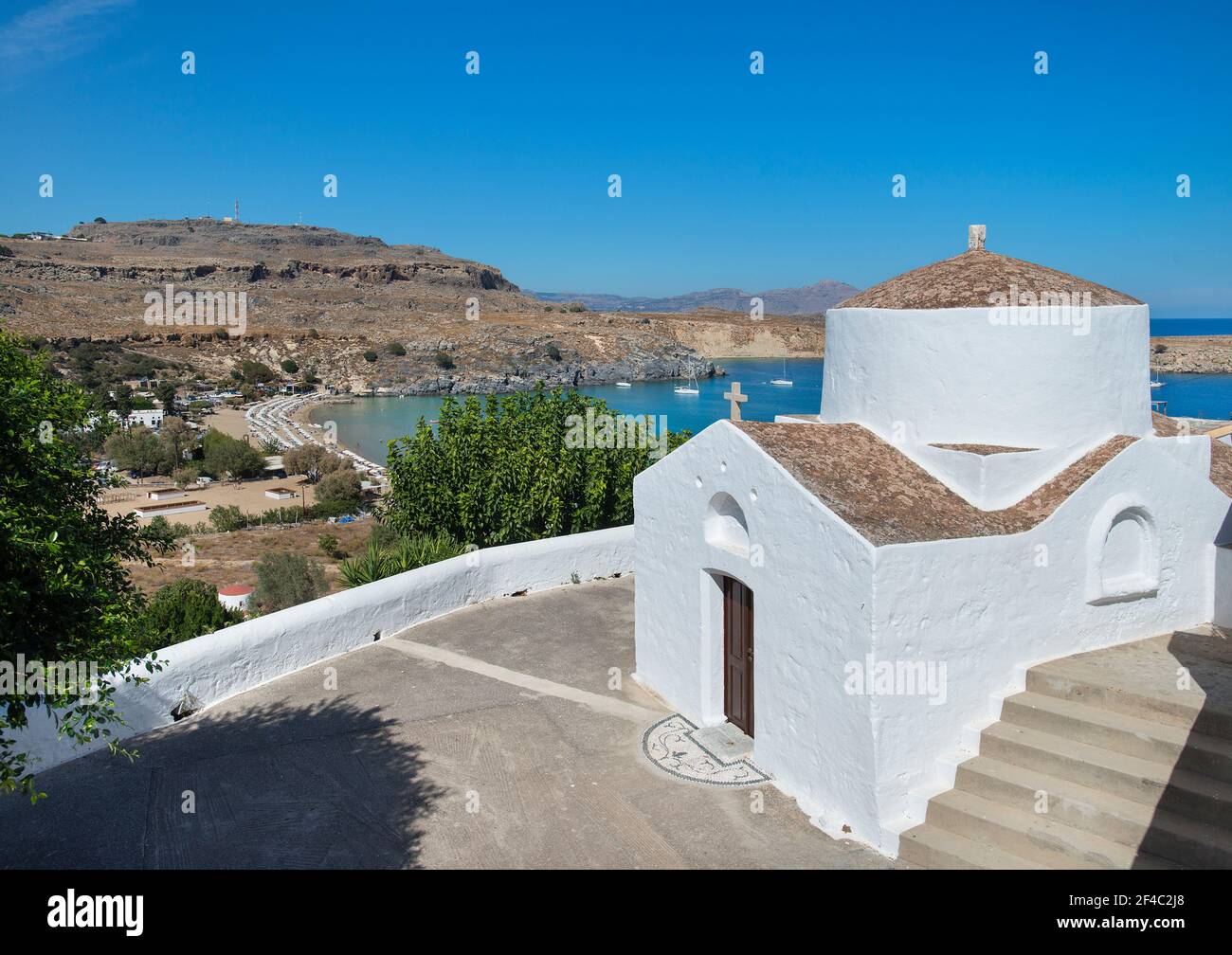 Greco ortodosso chiesa sulla collina con Lindos Beach, Rodi, Dodecanese, Grecia Foto Stock