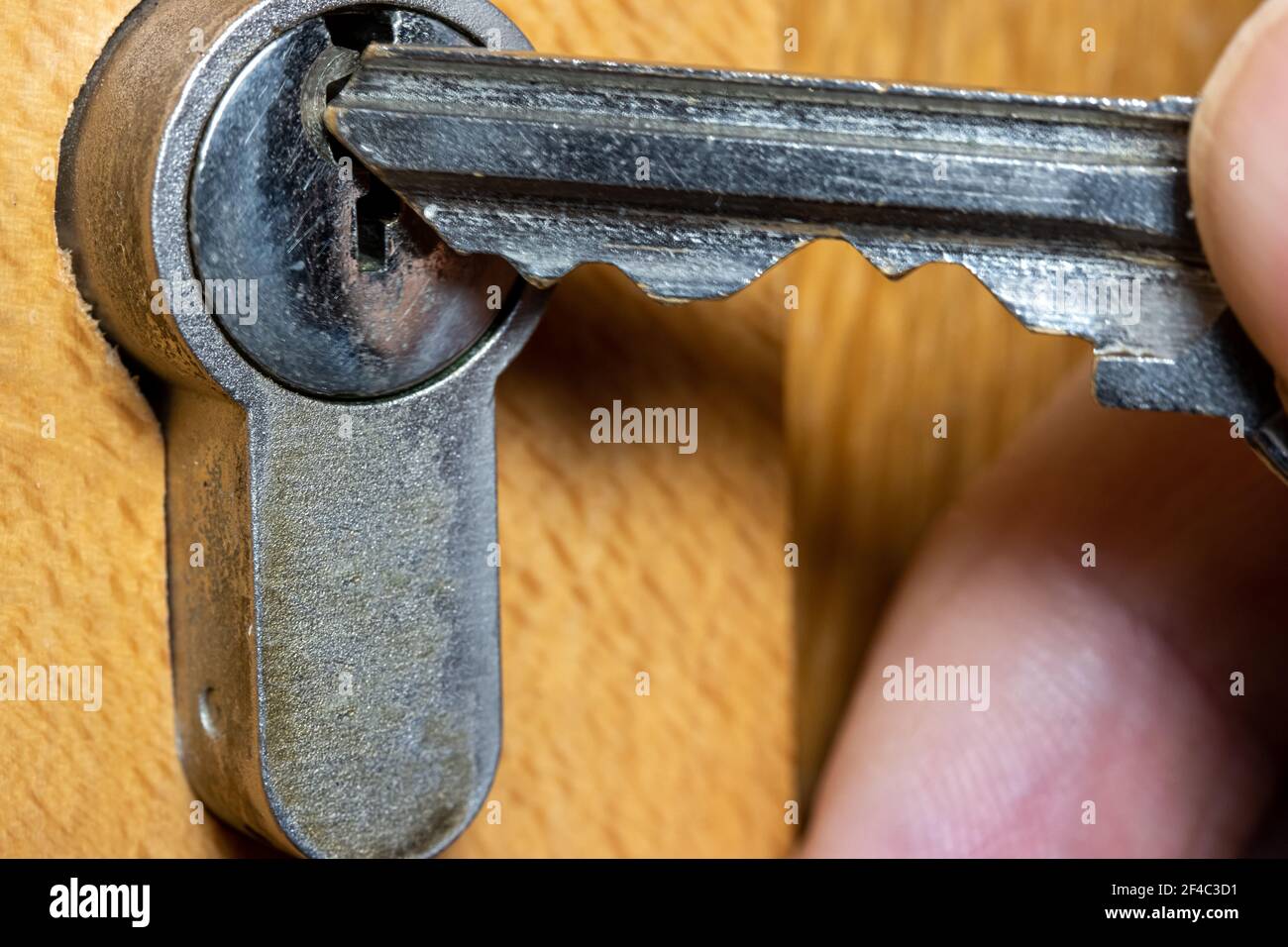 Una mano inserisce la chiave nel foro. La chiave inserita in una serratura di legno, vista ravvicinata. Foto Stock