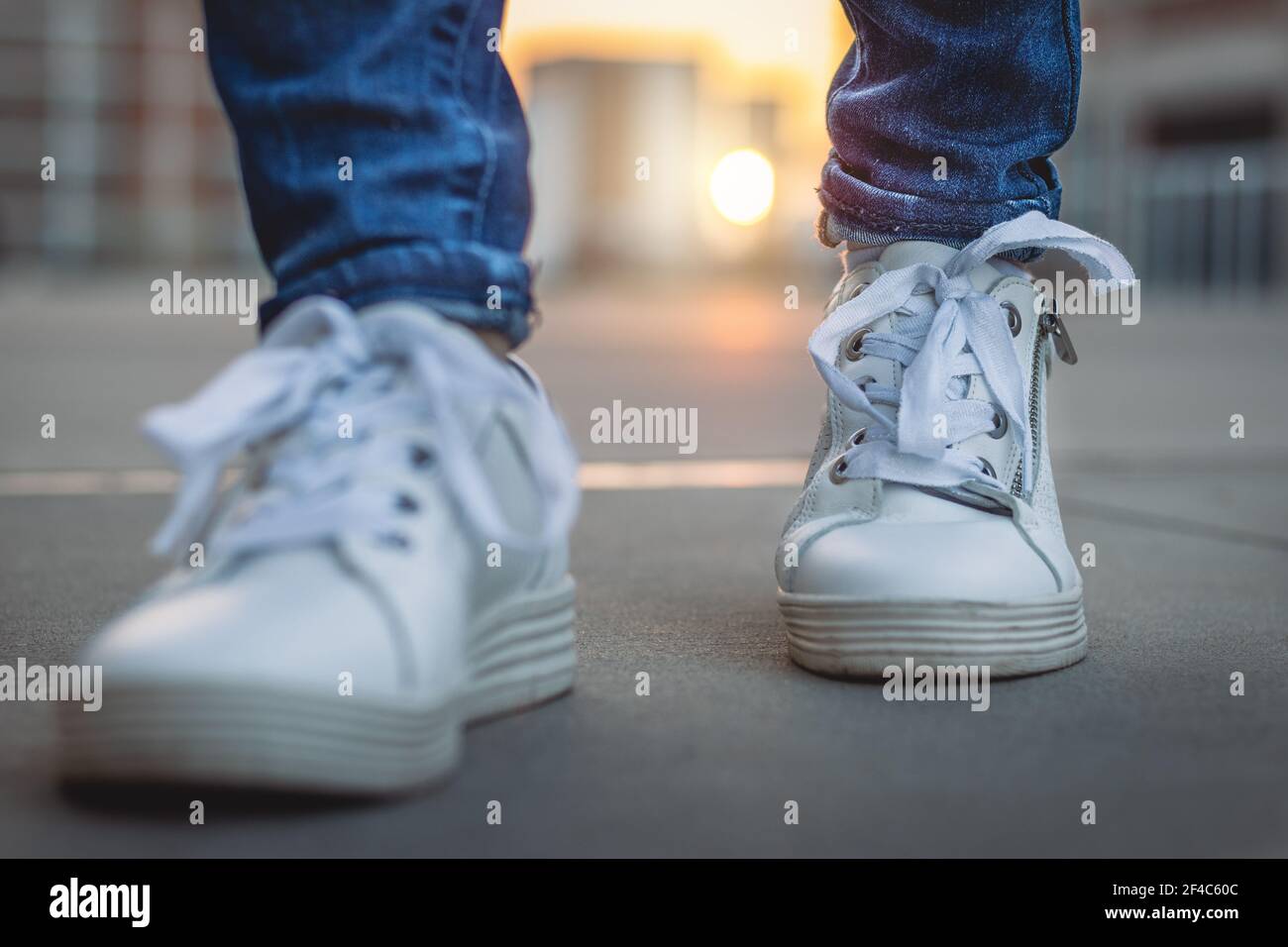 Sneaker bianche in città al tramonto. Camminare con le scarpe sportive  sulla strada. Vista frontale ravvicinata delle calzature all'aperto Foto  stock - Alamy