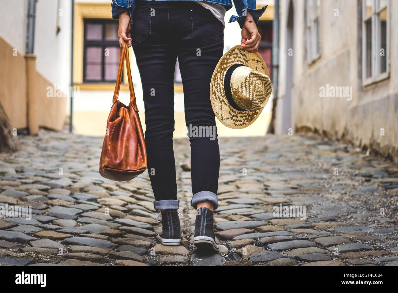 La donna indossa scarpe da ginnastica e cammina per strada nella città vecchia. Gambe umane con scarpe in tela Foto Stock