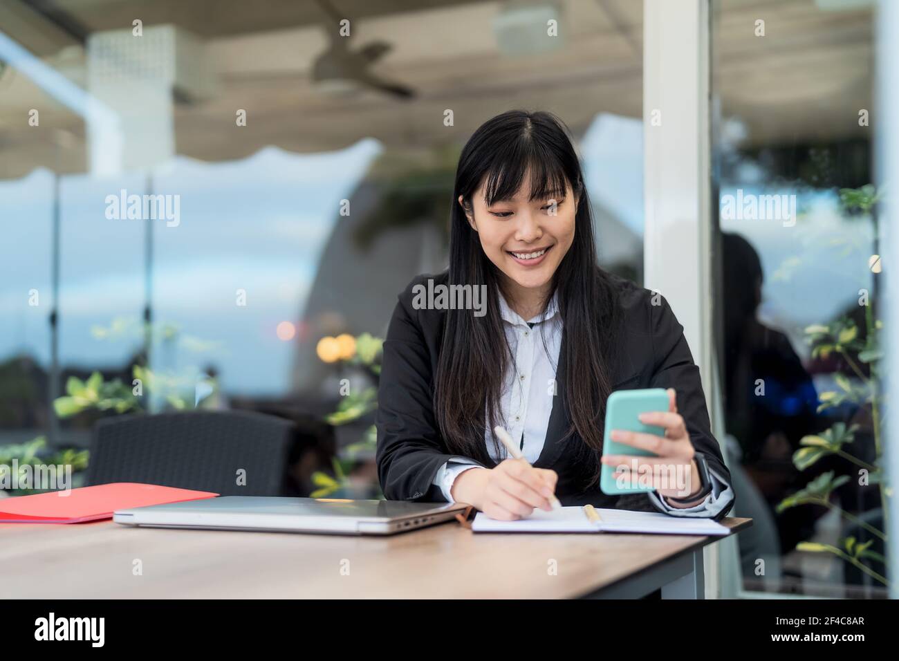 Donna asiatica d'affari che lavora con smartphone mobile in ufficio - Lavoro professionale e concetto di imprenditorialità Foto Stock