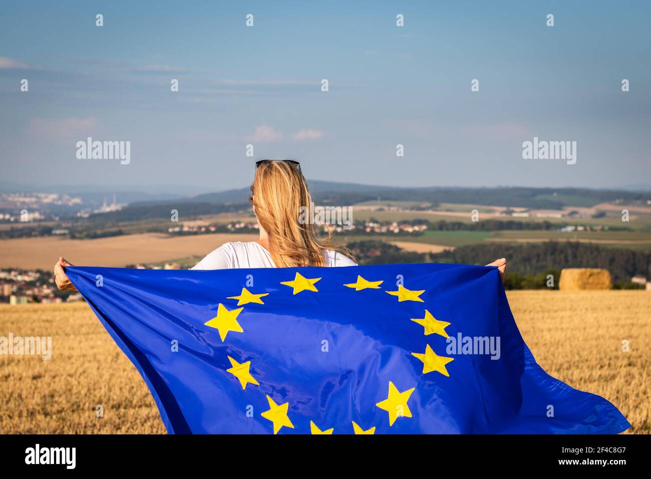 Donna che ha sventolato la bandiera dell'Unione europea in campagna. Bandiera dell'UE in mani femminili. Foto Stock