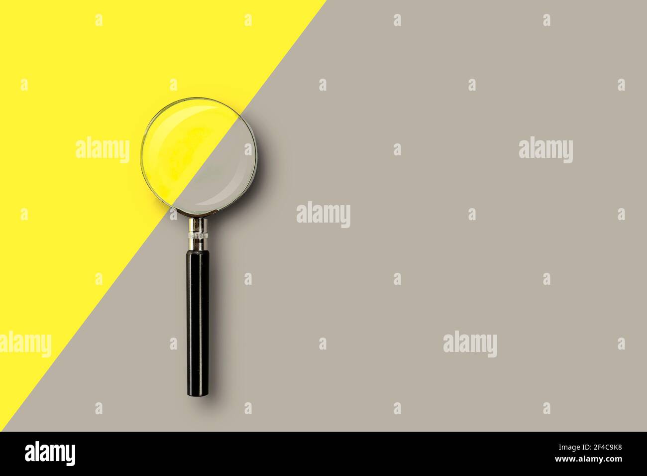 Lente di ingrandimento su sfondo giallo-grigio colorato con posizione per il testo. Foto Stock