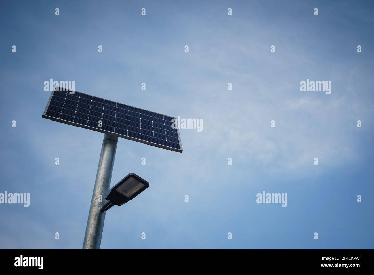 Illuminazione stradale a energia solare di fronte al cielo blu neutro con le nuvole di veli| Foto Stock