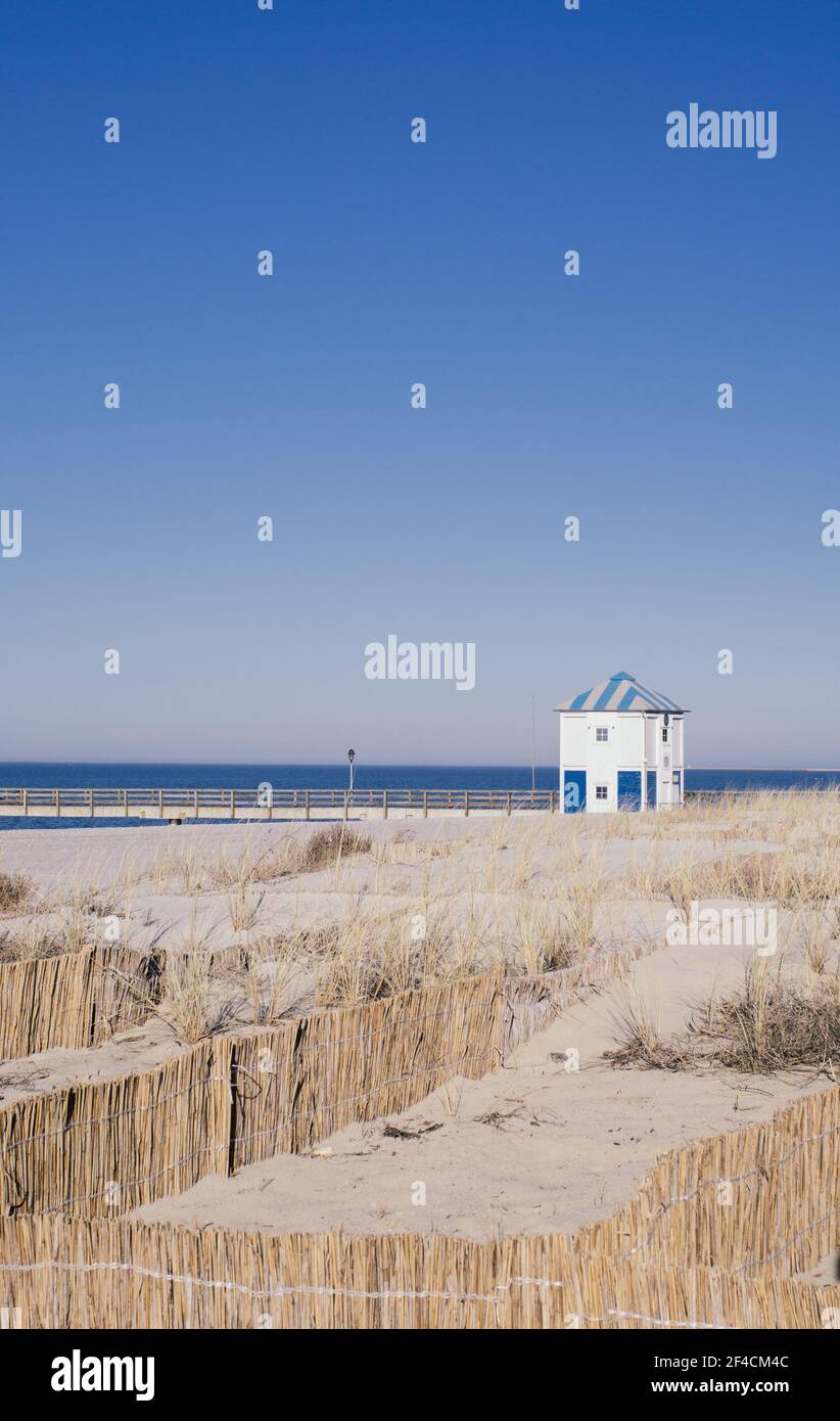 Casa di legno per il salvataggio dell'acqua e ponte dietro un dune con barriere di canna sulla spiaggia Foto Stock